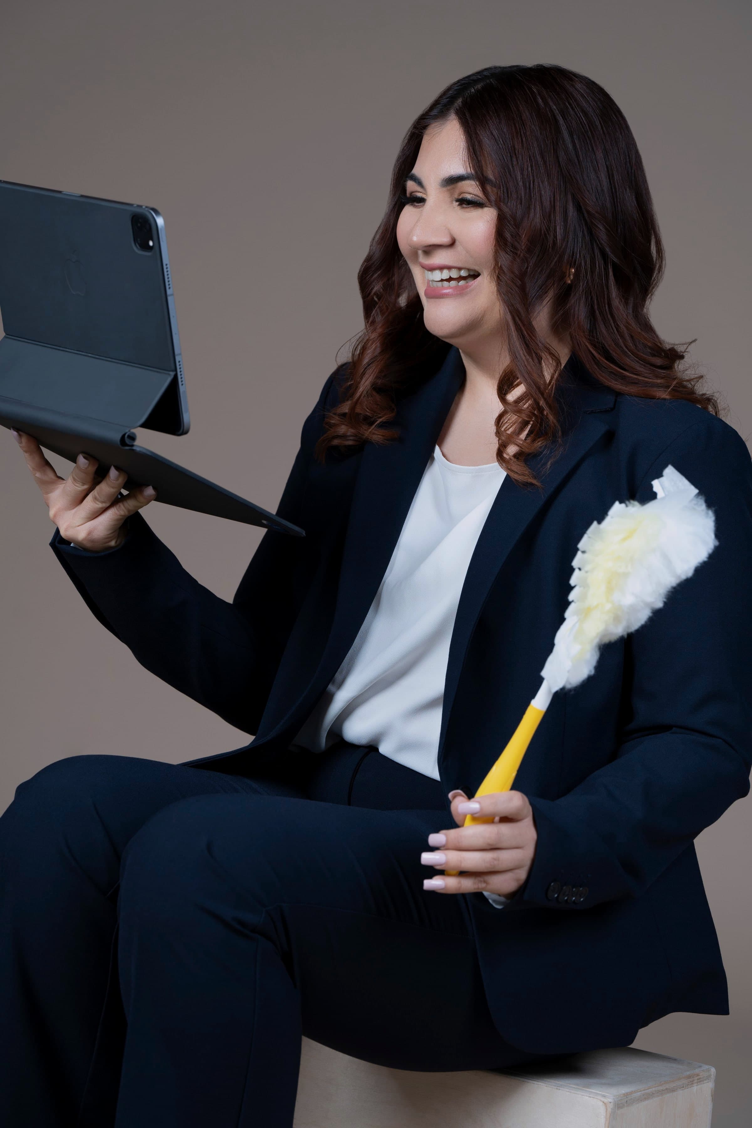 Krissia García sosteniendo una tableta y un plumero, riendo mientras explica