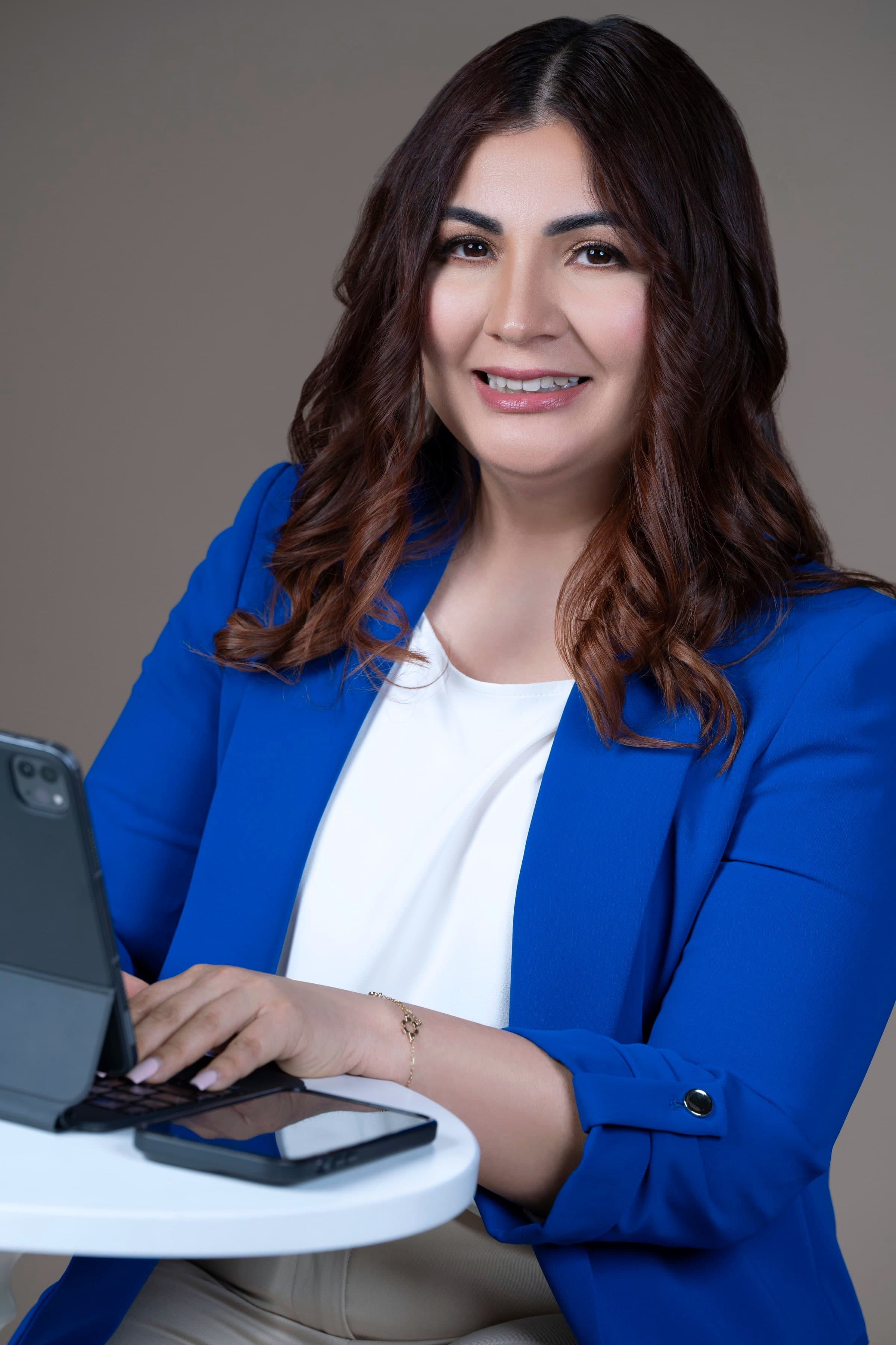 Krissia García sonriendo mientras escribe en una tableta, con el teléfono a un lado
