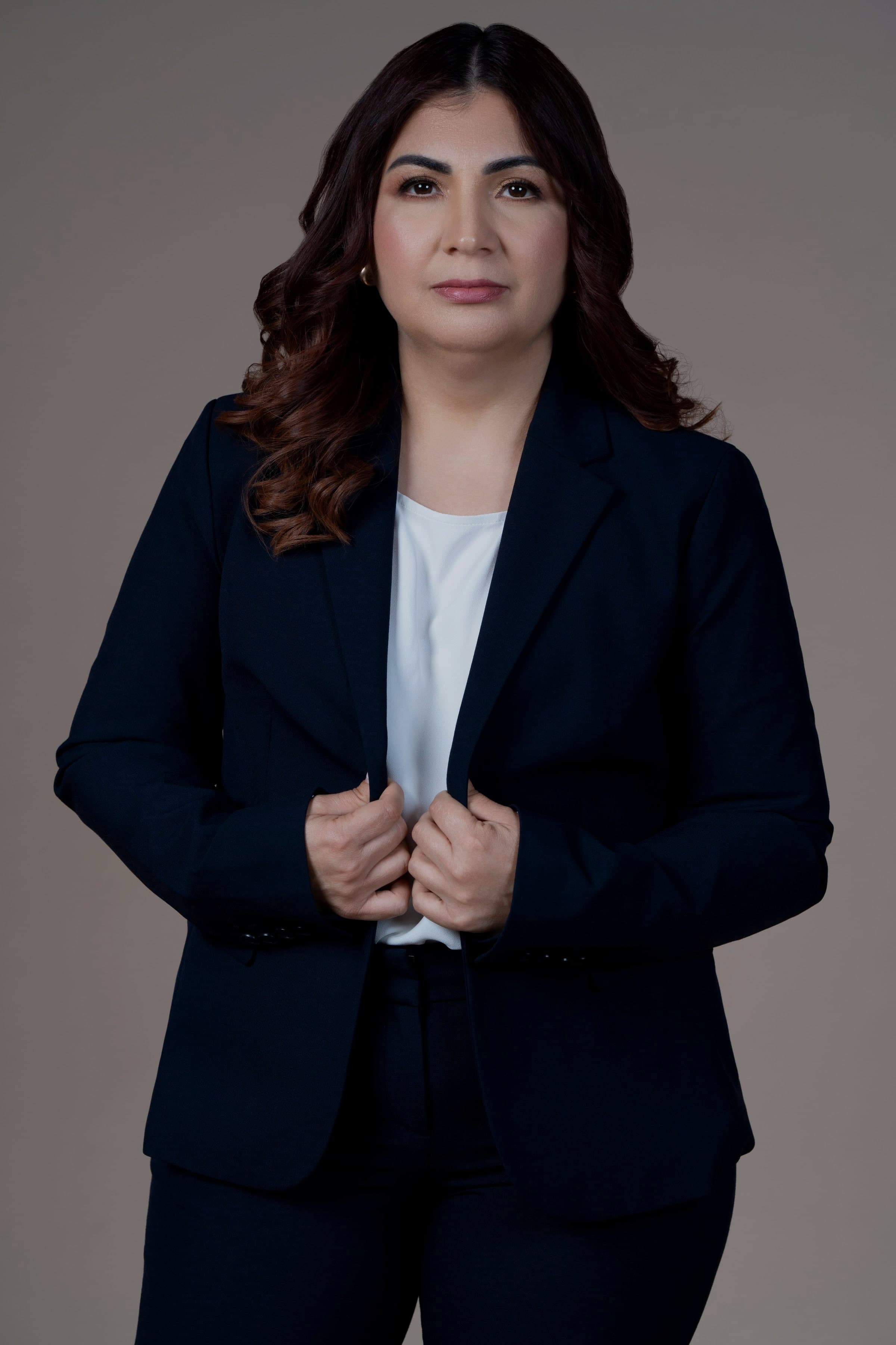 Krissia García con traje azul marino, mirando a cámara con las manos en la solapa