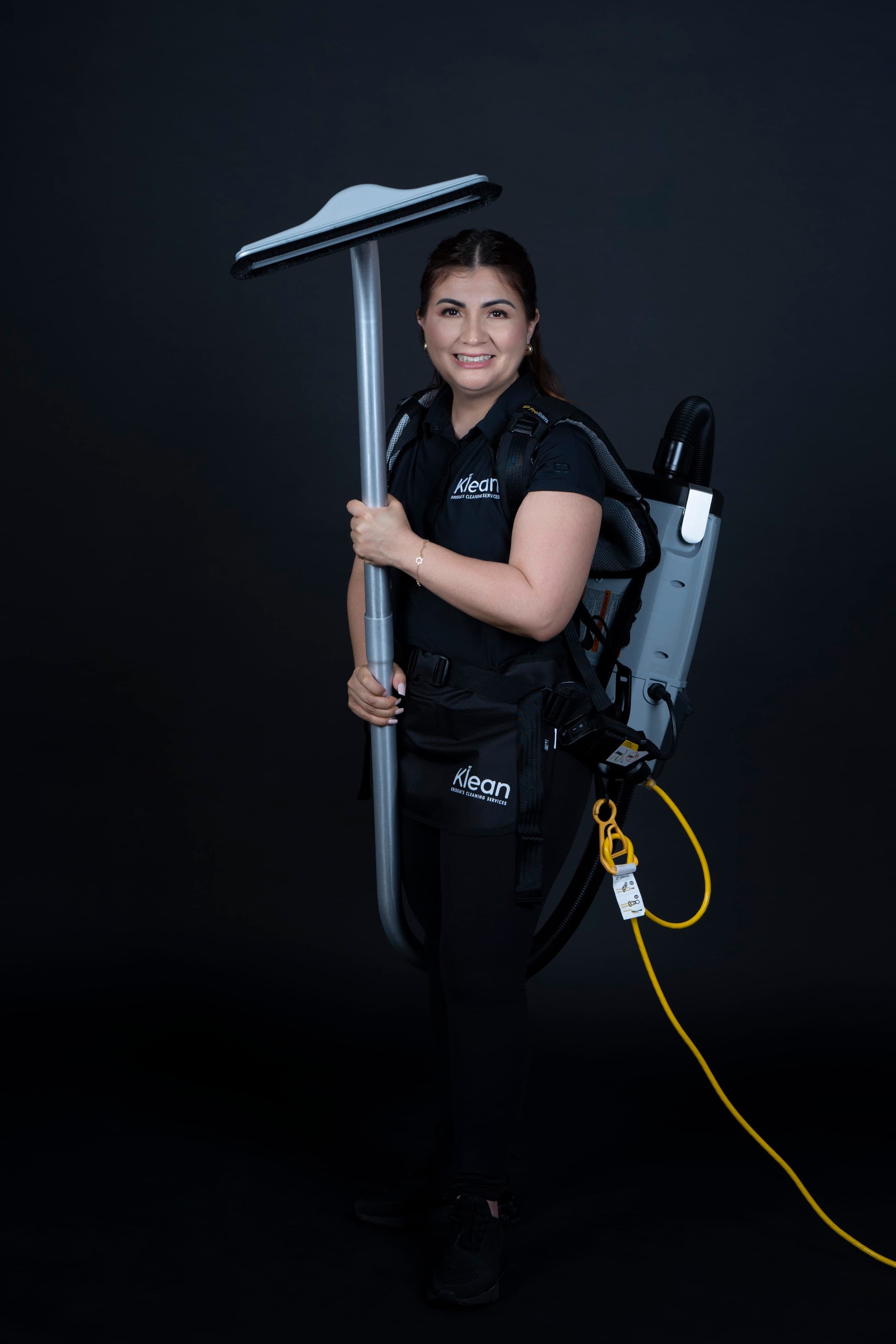 Krissia García con el uniforme de Klean y una aspiradora de mochila, haciendo el trabajo operativo