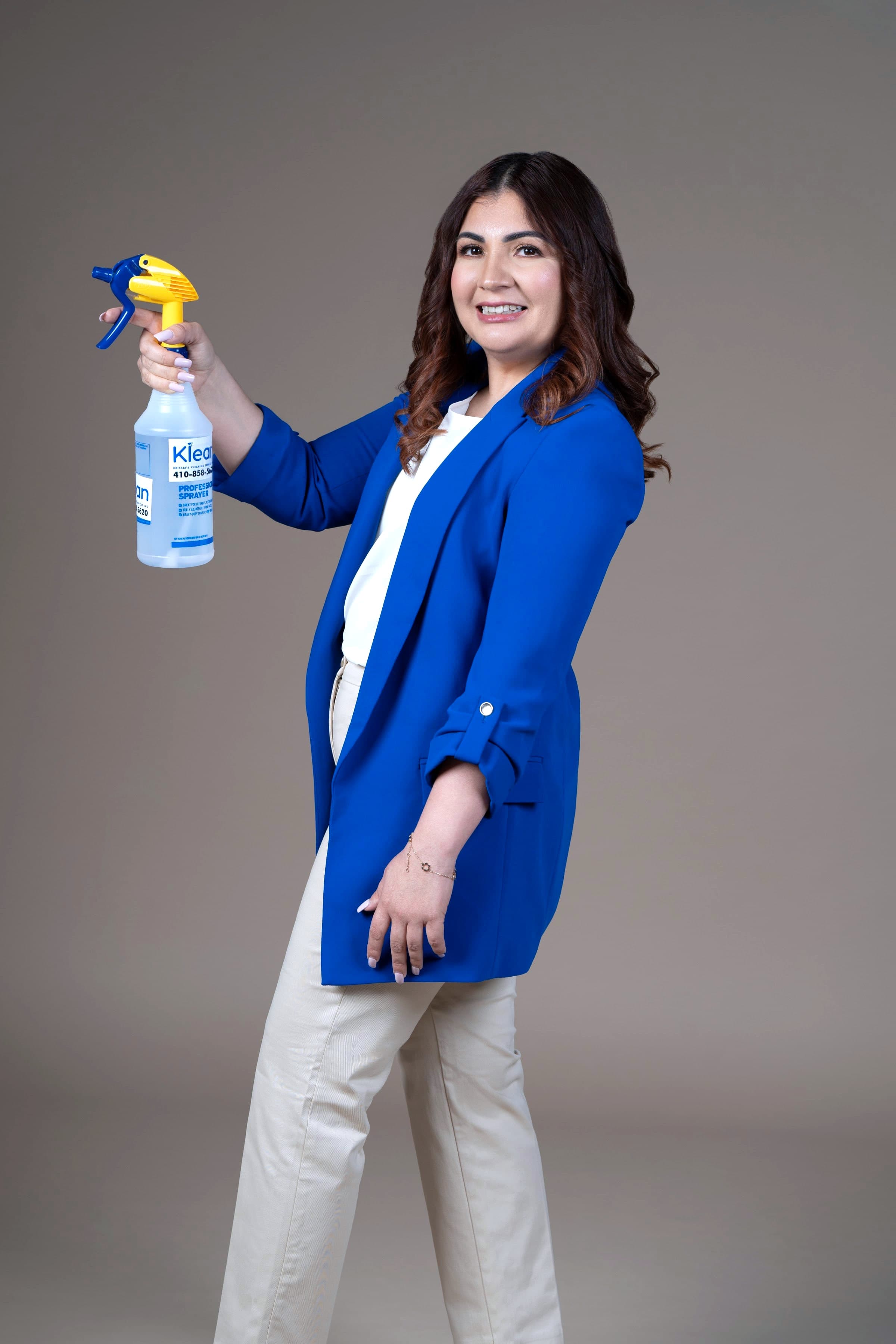 Krissia García con blazer azul, levantando un rociador de limpieza